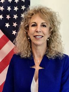 A woman smiling with an American flag behind her on the left side of the photo.